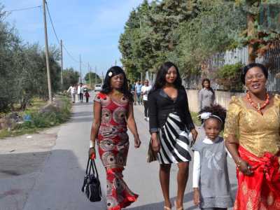 E' domenica mattina: i fedeli si dirigono eleganti verso la chiesa percorrendo a piedi una strada di campagna
